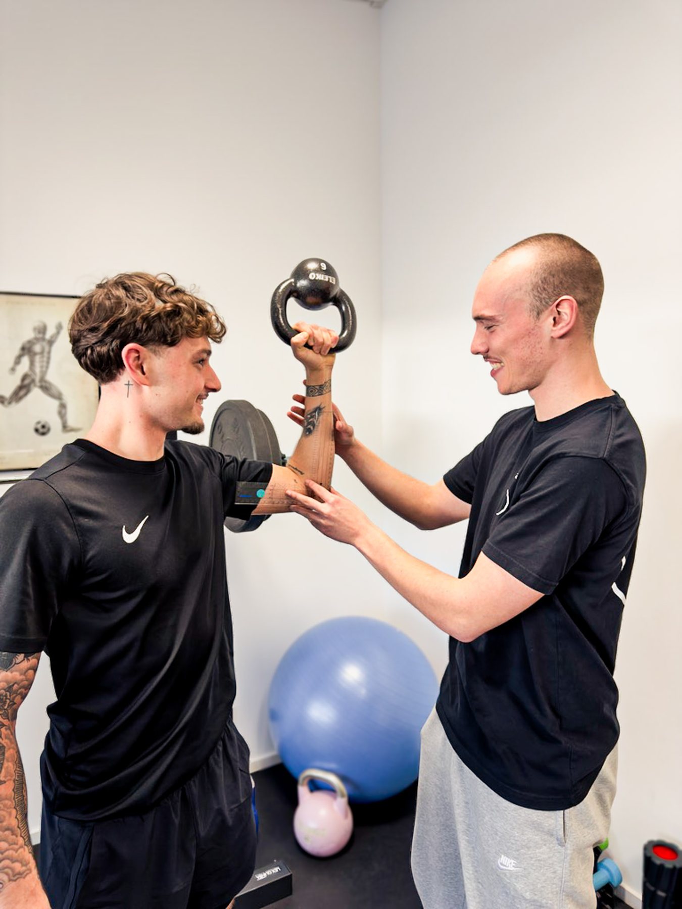 Aktive Therapie: Therapeut korrigiert einen Patienten bei einer Übung mit der Kettlebell